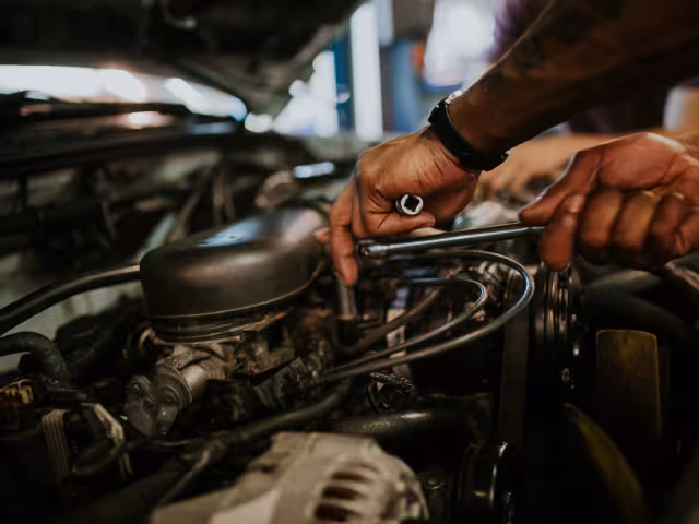 Students hand working on a cars engine