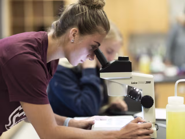 GRCC student looking into a microscope.