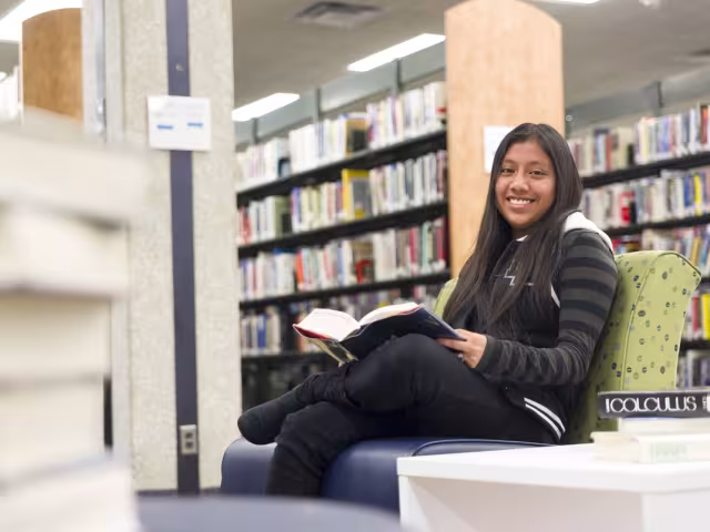 Student reading a book in the Library and Learning Commons.
