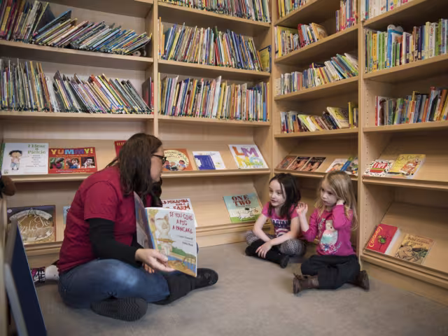 Student reading a book to two preschoolers