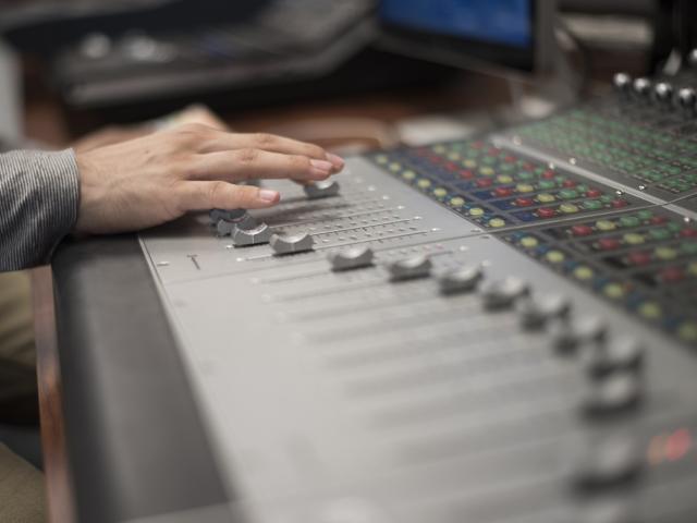 A student working a sound boud board in the recording studio.