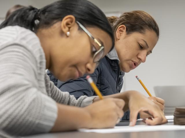 Two students taking a test with a pencil.