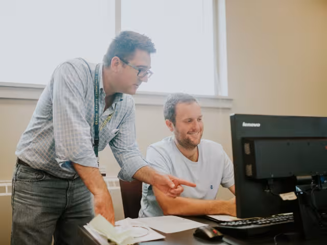 Professor reviewing a student's coding in a computer programming course.