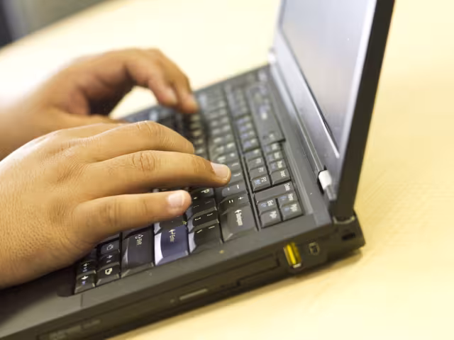 Student typing code on laptop.
