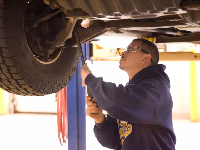 Automotive student working on the underneath of a car