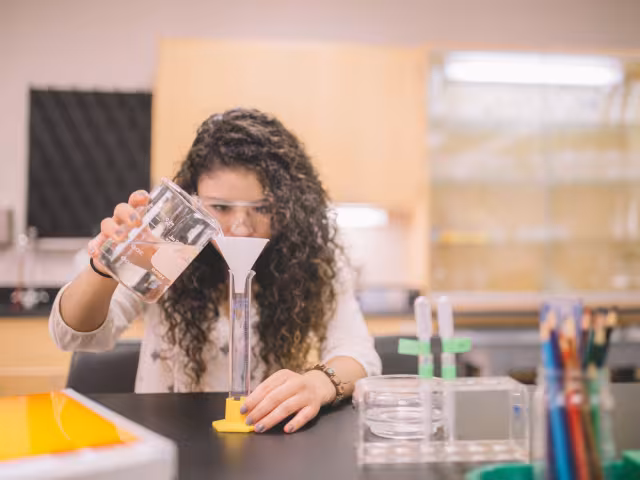 Student pouring solution into a measuring cup