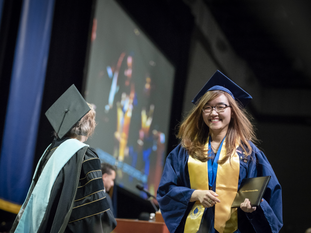 Student walks across stage at Commencement.