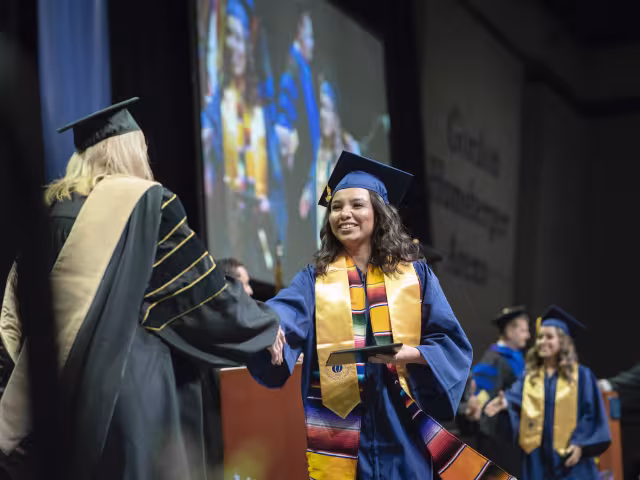 Student shaking hands with leadership as they receive their diploma.
