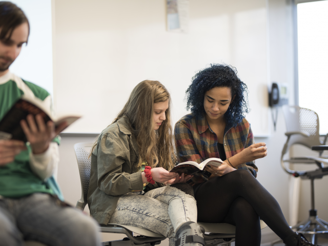 Students reading from the same book in an English class.