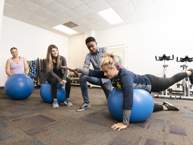 Students work on physical therapy stretches with a yoga ball.