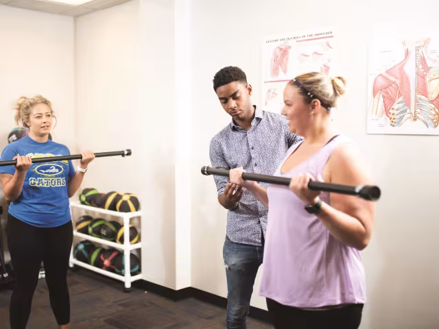 Students work on weight lifting form in an Exercise Training class.