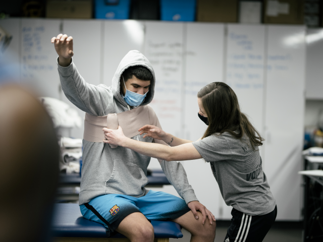 A student wraps an athlete's muscle.
