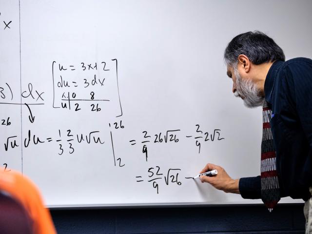 Math professor writing on the whiteboard. 