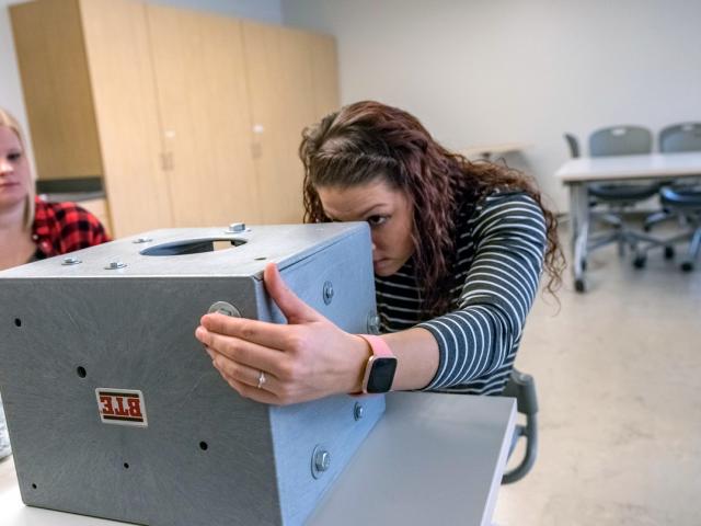 Occupational Therapy Assistant student working with a box in the classroom.