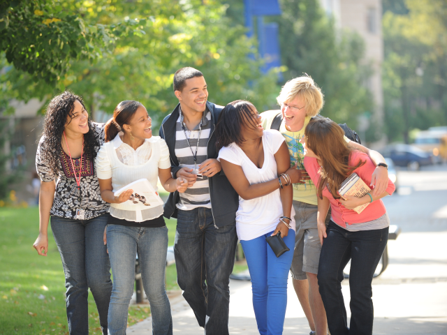 A group of students laughing and walking on campus.