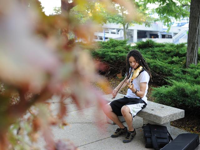 GRCC music student outside playing the violin