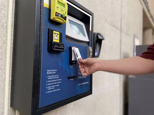 A student using the new RaiderCard machine to add money to their card.