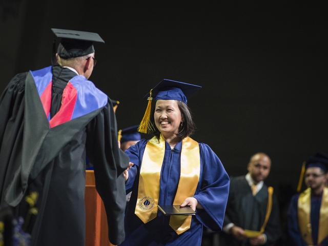Student receives diploma on stage.