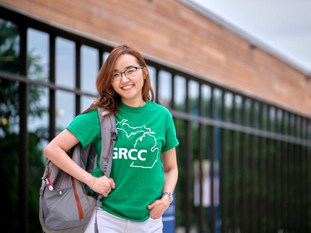 GRCC student smiling wear a green GRCC shirt and standing outside the Preschool