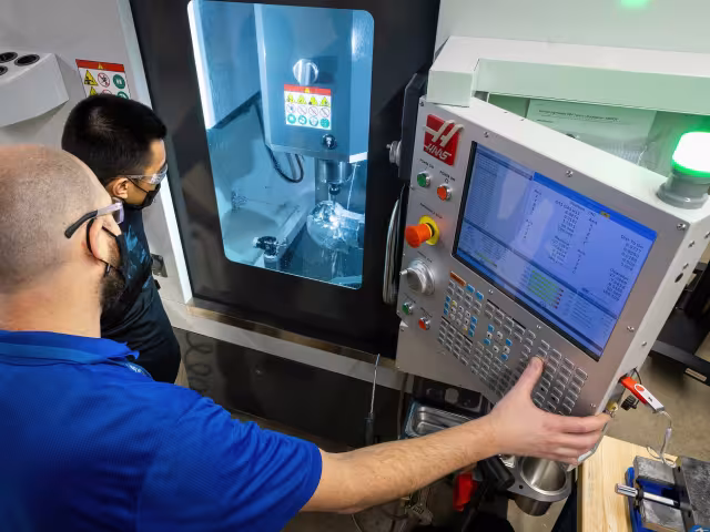 Manufacturing student using a machine to make a metal piece
