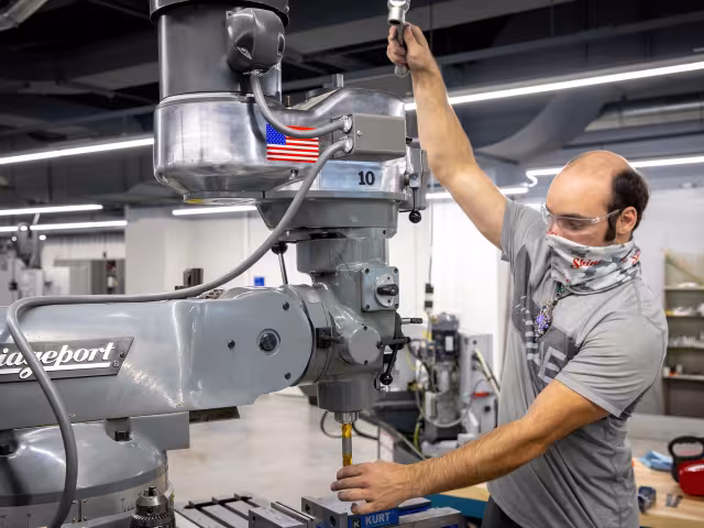Manufacturing student using a large machine to sculpt metal