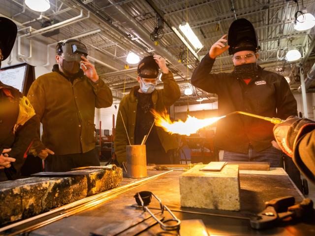 A group of welding students watching a demostartion