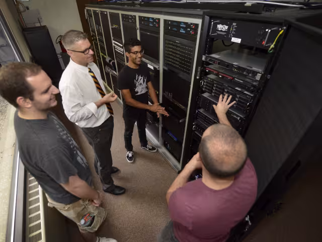 Professor works with students on server racks.