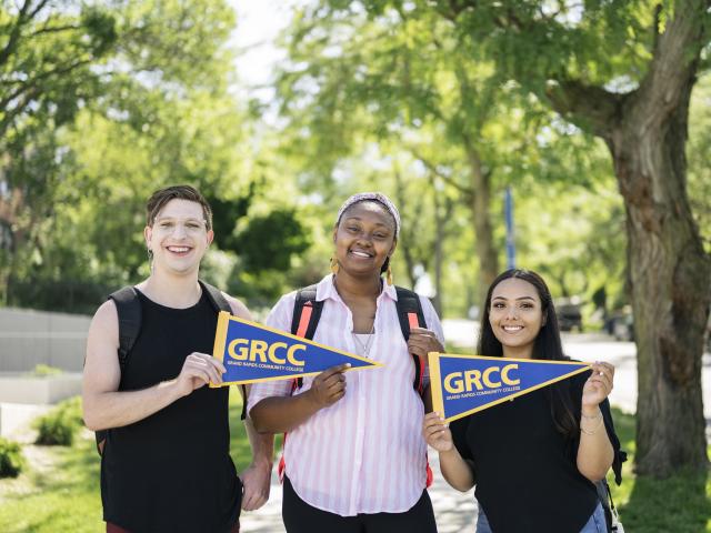 Students smiling and holding GRCC pennants. 