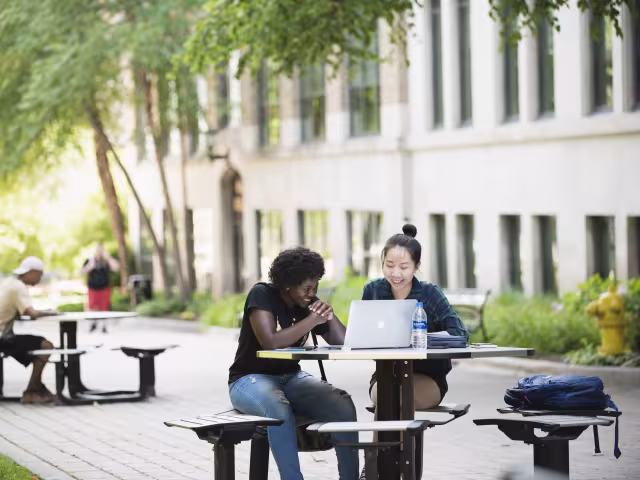 Students working together on laptop on Bostwick Commons.