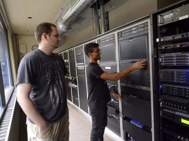 Students in a cybersecurity class working on a server rack.