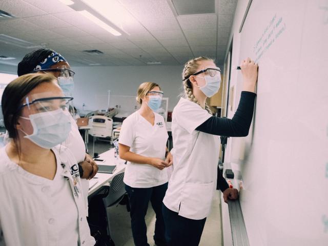 Students taking notes on a whiteboard in a health class.