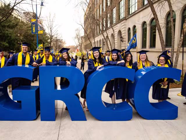 Graduates in front of large letters spelling GRCC.