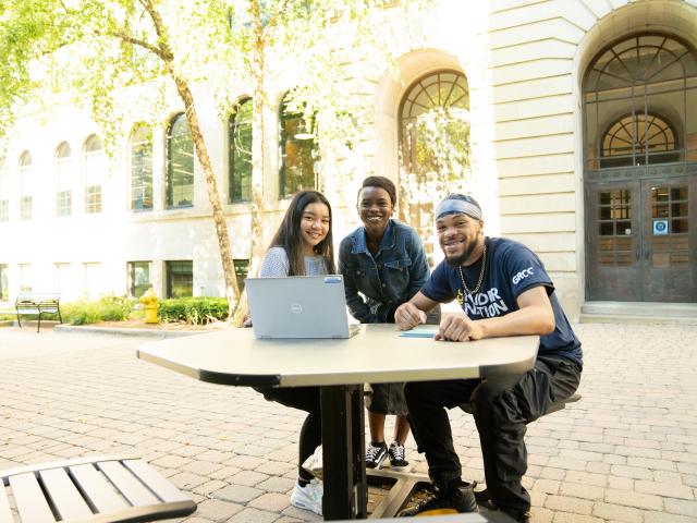Three promise zone students on the commons with a laptop
