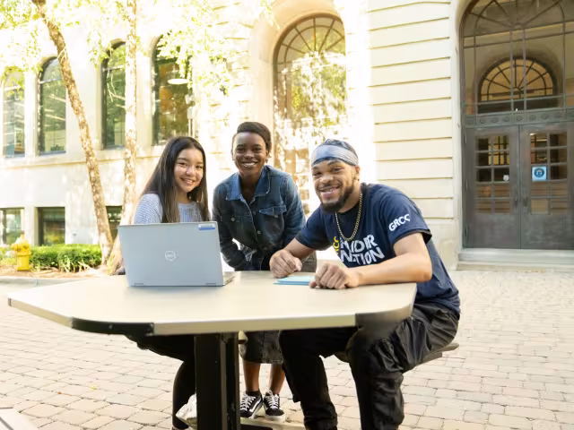 Three students working on a laptop