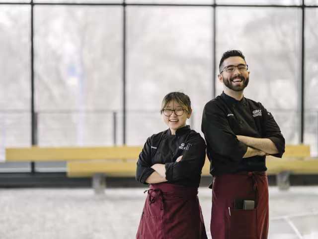 Two student chefs stand with crossed arms