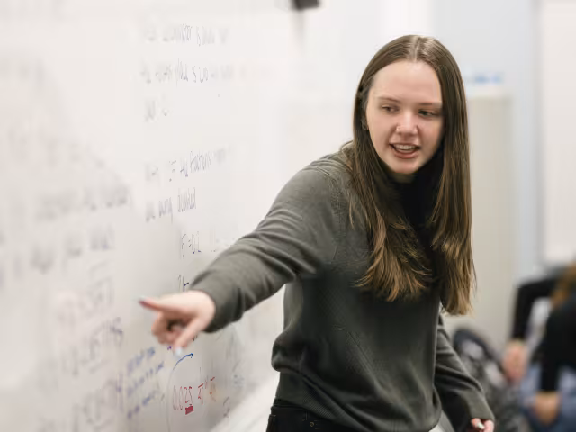 A person points to a whiteboard.