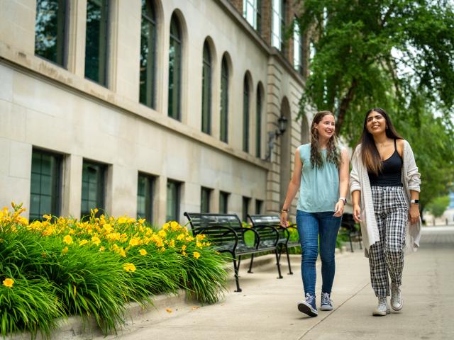 Two guest students walk side by side on GRCC's main campus.