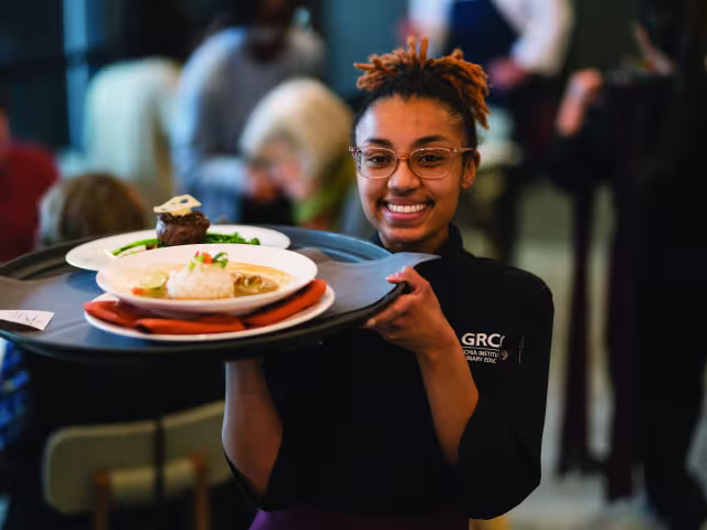 Culinary student carrying a tray of food